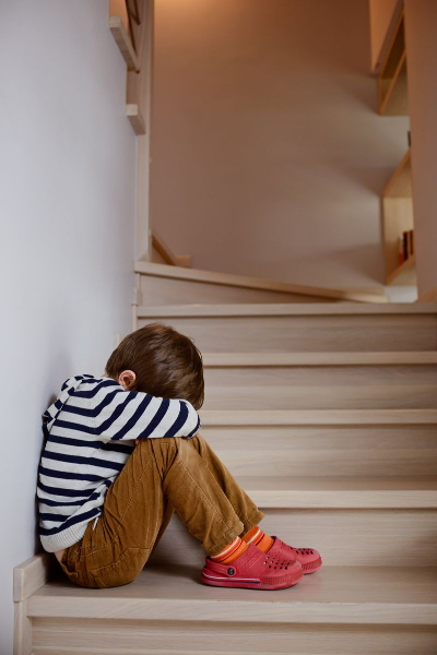 Little boy sitting on stairs in time out.  Time out for kids.