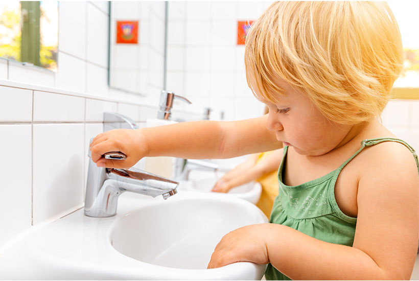 Little child washing hands in small sink.